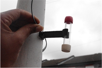 A hand next to the diffusion tube that is attached to a post in a vertical position with the coloured cap at the top..