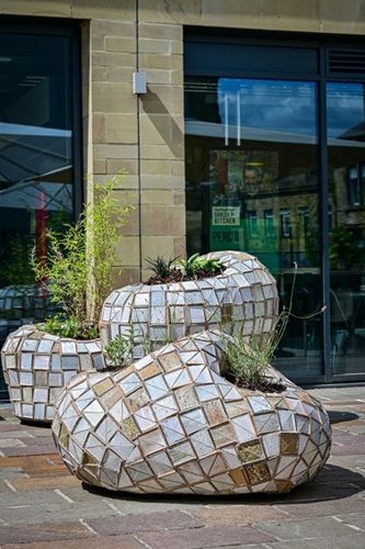 A planter made from the tiles from the artwork, with plants growing in them.